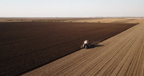 Tractor Plowing Vast Farmland From Above on Sunny Day