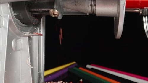 I sharpen a red pencil, shavings fly. Dolly slider extreme close-up.