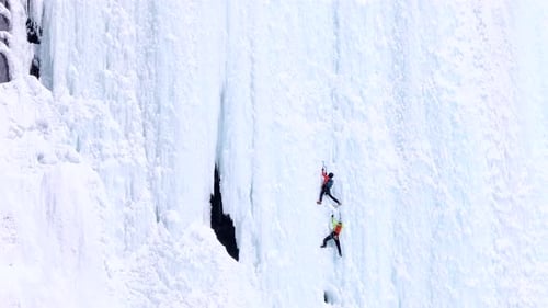 Zwei Eiskletterer am Hochseil erklimmen den steilen technischen Abschnitt der Route