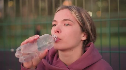 Young Woman Drinks Water After Outdoor Exercise