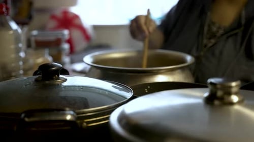 Person Cooking Food in a Pot at Home