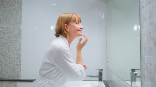 Woman Applies Moisturizing Cream in Bathroom