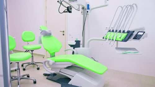 empty modern white and green dentist's office in clinic with computer equipment dental chair