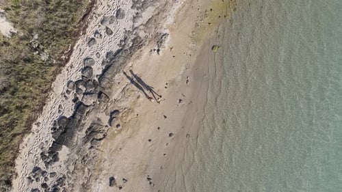 4K Aerial shot of two people friends walking on paradise beach at sunset big shadows