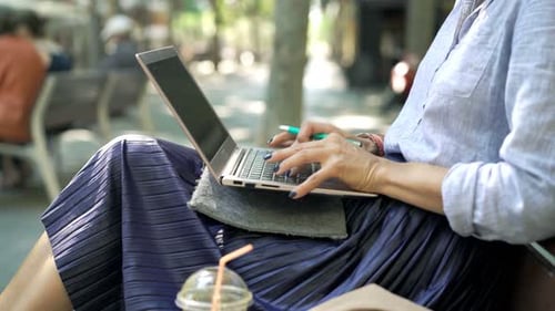 Young businesswoman working on laptop sitting on bench in the city outdoors