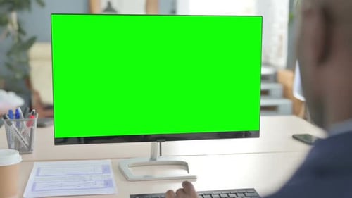 Young African Businessman Working on Computer with Green Screen in Office