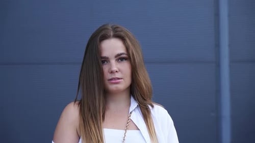 Portrait of young Caucasian girl in white shirt posing for camera. Close-up