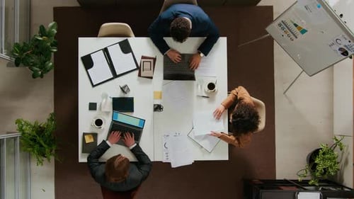 Top Down of Two Young Men and Woman Working at White Table in Office Setting
