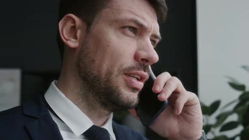 Close-Up of Businessman Talking on Mobile Phone beside Office Window