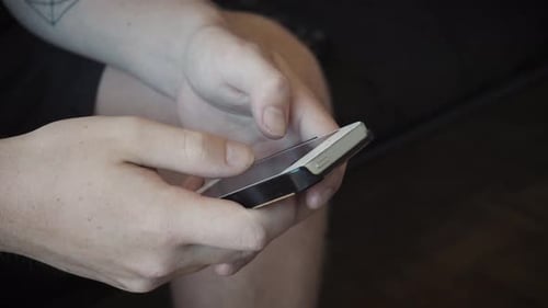 Static shot of a man texting and navigating a smart phone.