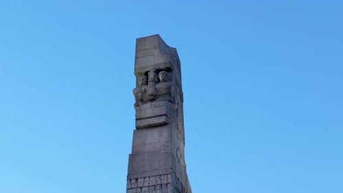 Monument rising above greenery under clear blue sky, symbol of national pride and remembrance.