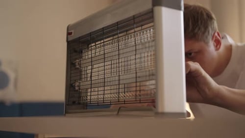 Man Examining an Electric Fly Swatter Indoors