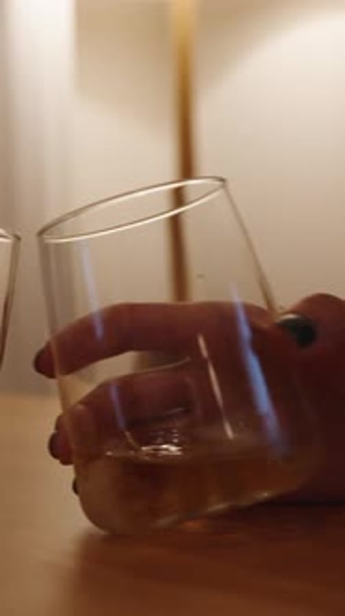 Hands Holding Glasses of Golden Liquor