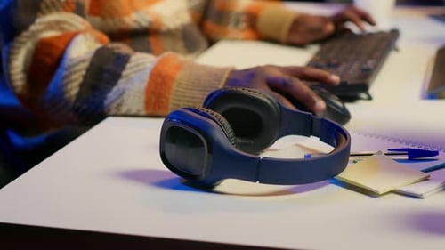 Man Puts on Headphones at Desk at Night