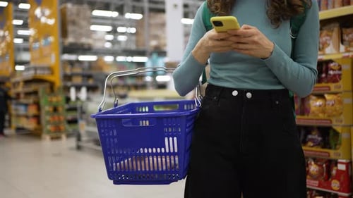 Woman Using Smartphone While Shopping in Supermarket