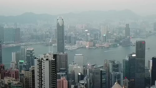 Aerial shot of skyscrapers in city with sea against sky during sunset, drone flying over modern buil