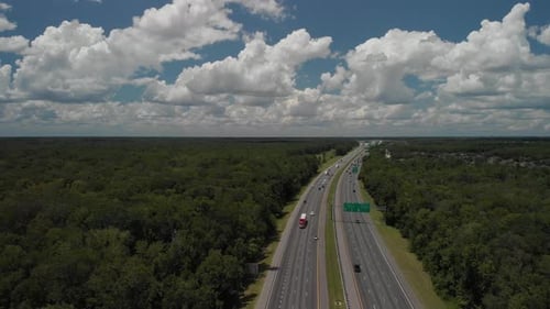 Panoramaaufnahme der Drohne, die die Autobahn und die Straßen zeigt, Autos, die an blauem Himmel, weißen Wolken, Bäumen vorbeifahren
