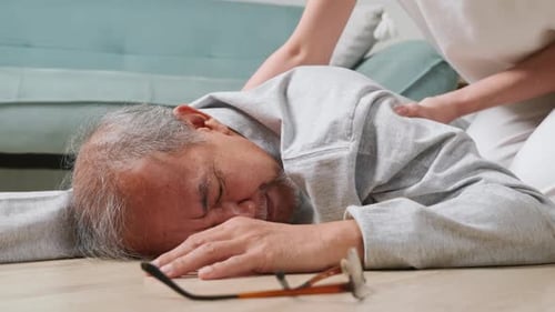 Adult Assists Senior Man on Floor at Home