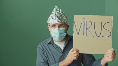 Man Wearing Mask and Foil Hat Holding Virus Sign