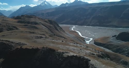 Autumn aerial of a high altitude rocky mountain range with river stream below. Surreal panoramic lan