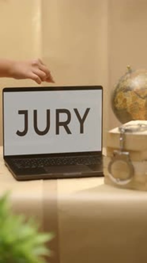 Laptop Screen Displays the Word JURY on Desk