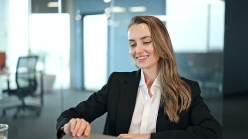 Relaxed woman in business suit leans back at desk