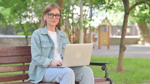 Young Woman Smiling with Laptop in Park