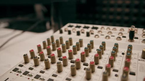 professional recording studio sound engineer with finger adjusts volume level on mixing console