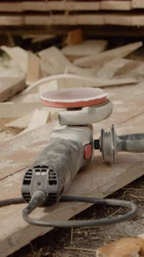 Vertical video Angle grinder resting on wooden beams after completing wood sanding process