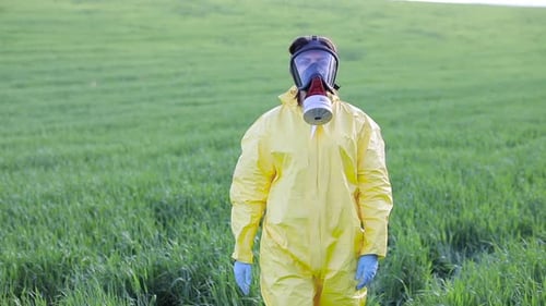 Person in overalls and gas mask call to save the planet while standing on green field on sunset