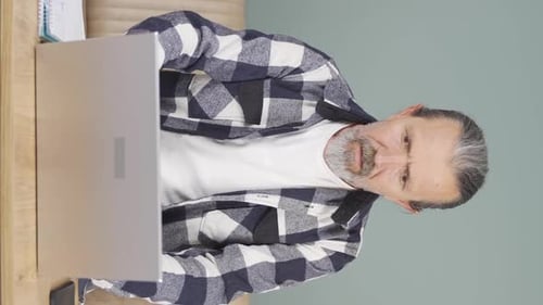 Vertical video of Old man looking at laptop gets frustrated.