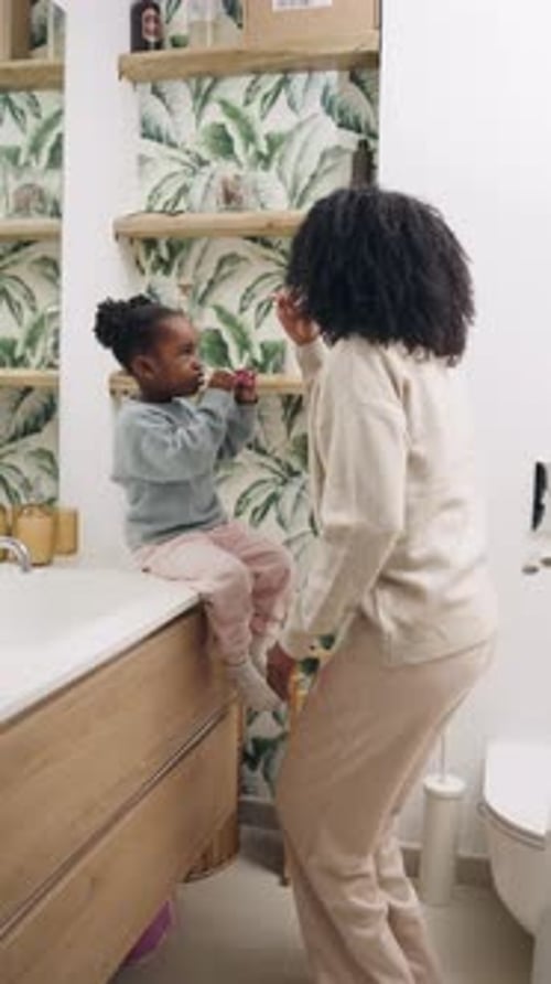 Mother and Child Brushing Teeth in Bathroom Together