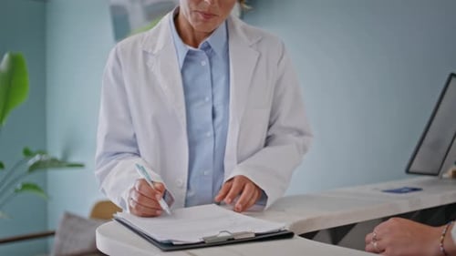 Healthcare Specialist Signing Papers at Clinic Reception Closeup Smiling Woman
