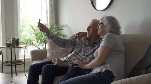 Senior Couple Taking Selfie on Couch in Living Room