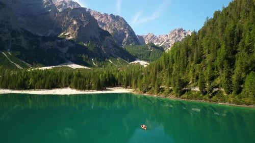 Aerial View of a Turquoise Alpine Lake Lush Pine Forest and Rugged Mountain Peaks