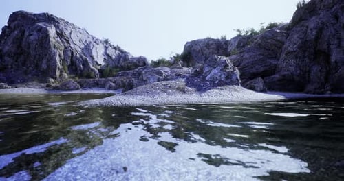 Rocky Shoreline with Calm Water Reflecting the Clear Sky at Midday