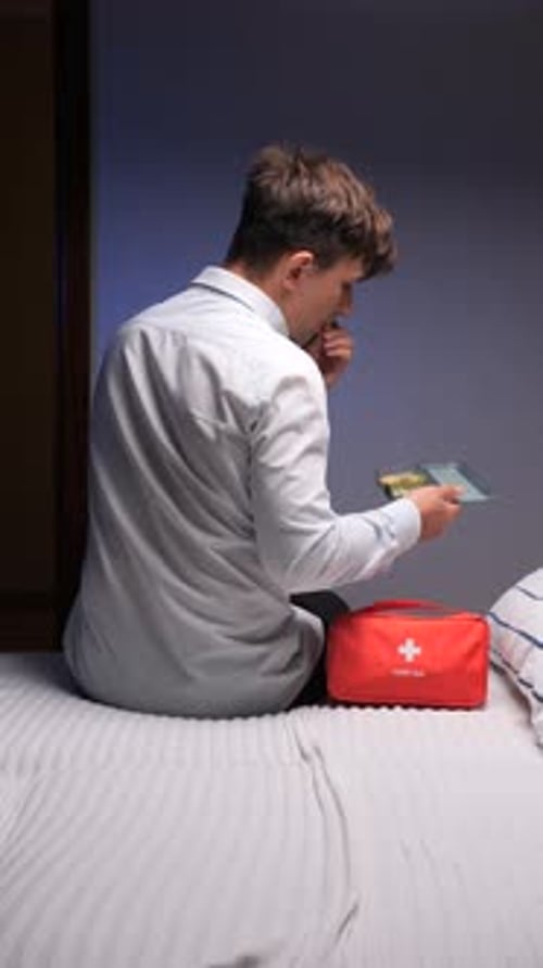 Young Man Taking Medicine with Water Before Bed