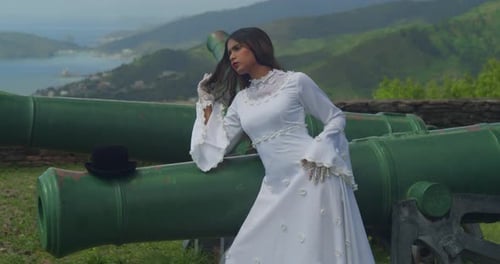 A girl in a classic vintage bridal dress poses gracefully on a historic fortress.