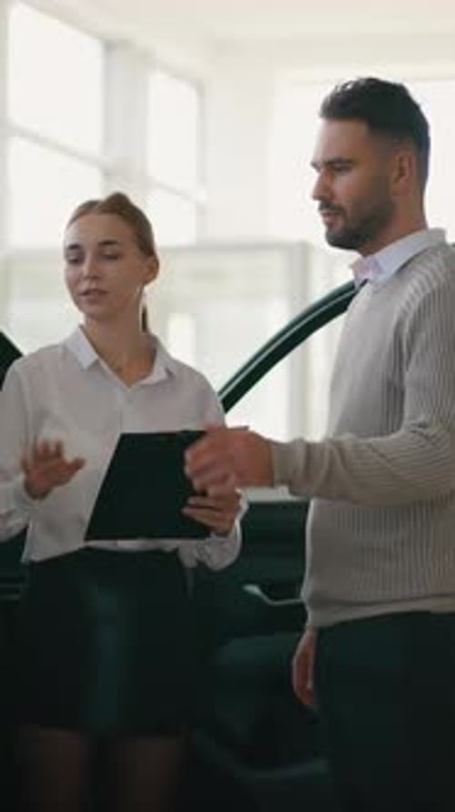 Professional Car Saleswoman Consulting a Male Customer in a Dealership Showroom