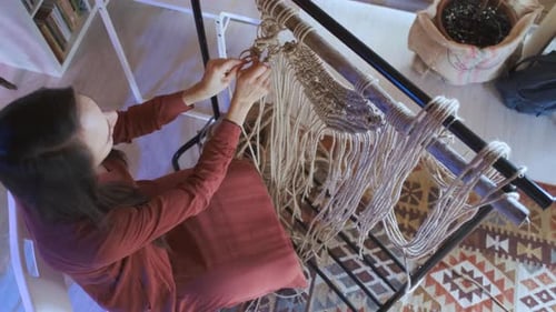 top view woman in dress weaves macrame sitting at home