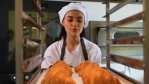 Chef Places Croissants Onto Rack in Bakery Kitchen