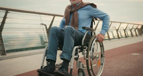 Focused Man Propels Wheelchair Forward on Bridge Walkway