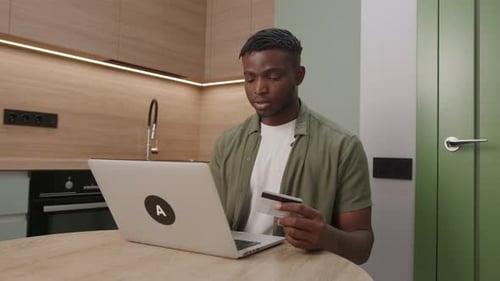 Black Man Paying Online Using Laptop and Bank Card African American Man Making Internet Purchase