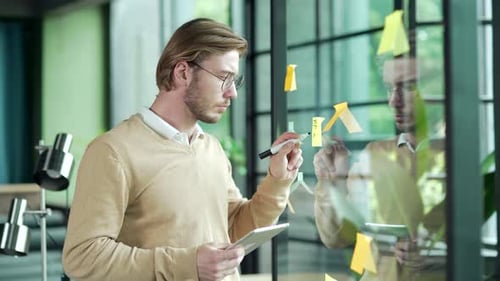 Busy bearded business man employee work with tablet gadget write idea on paper sticker sticky notes