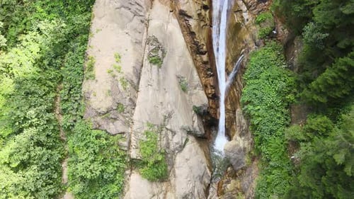 Waterfall Cascading Down Rocky Cliffside in Lush Landscape