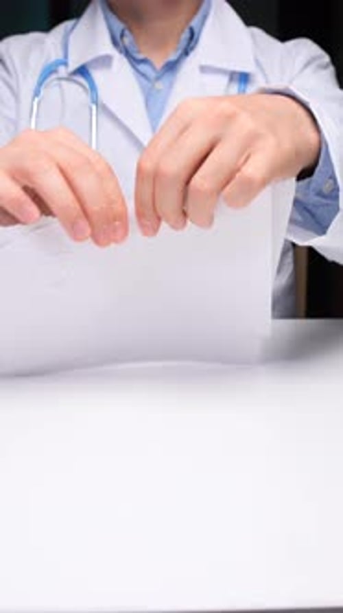 Vertical Video Medical Professional in a Lab Coat and Stethoscope Tearing a Document on a Desk