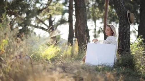 Dame en tenue blanche assise parmi les arbres dans les bois