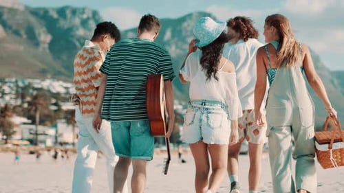 Friends, picnic and walking on beach for travel with basket, rear view and wind for vacation