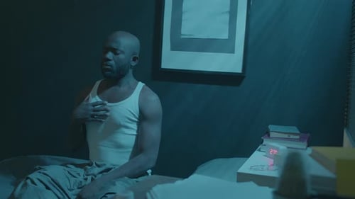 Man Meditating on Bed in Dark Room