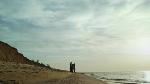 Family silhouettes walking on the beach enjoying a beautiful sunset sea coast
